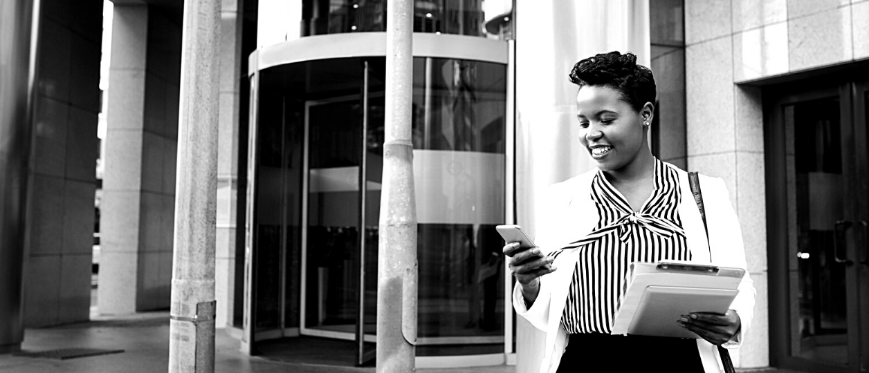 a woman looking at her phone walks out of a building