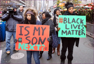 people protesting with two signs: 'is my son next?' and '#BlackLivesMatter'