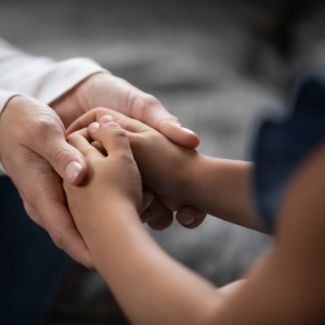 pair of adult hands holding a pair of child's hands