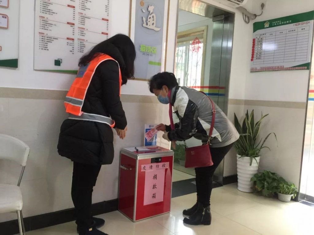 Woman contributing to the Lujiazui Community Foundation’s counter-pandemic fund while another woman looks on.