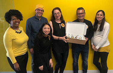 Two men and four women from Candid's Oakland office celebrate Candid's first anniversary with cupcakes.